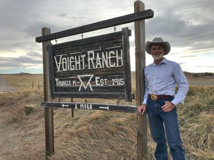 John Voight standing next to wooden sign